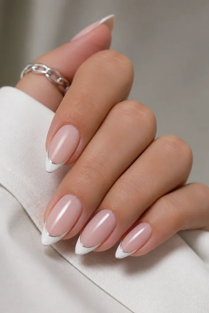 Short stiletto nails with a sheer pink base. The French tip is white, and there's a super thin metallic silver line tracing the edge of the white.