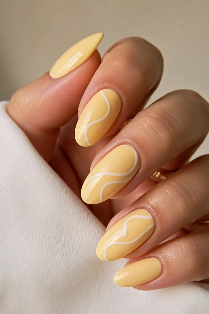 Accent nails show a simple floral stamp drawn in pale white and soft yellow tones, placed near the tip. Background nails are solid light yellow, glossy finish.