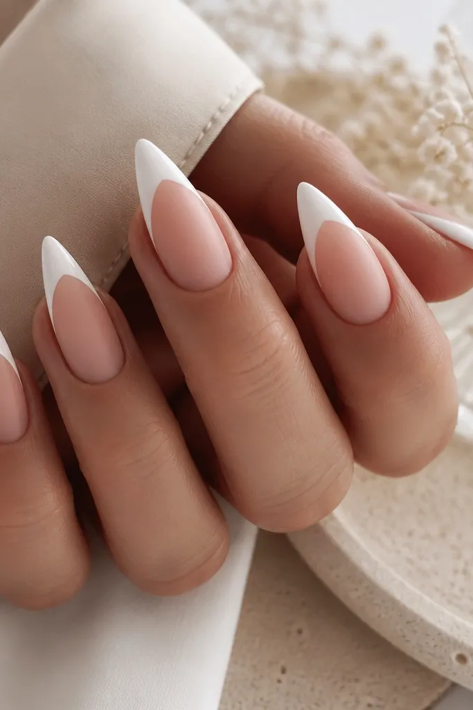 Short stiletto nails where the base is matte nude. The french tips are glossy bright white, creating a strong contrast between matte and shine. The tips have a crisp smile and taper.