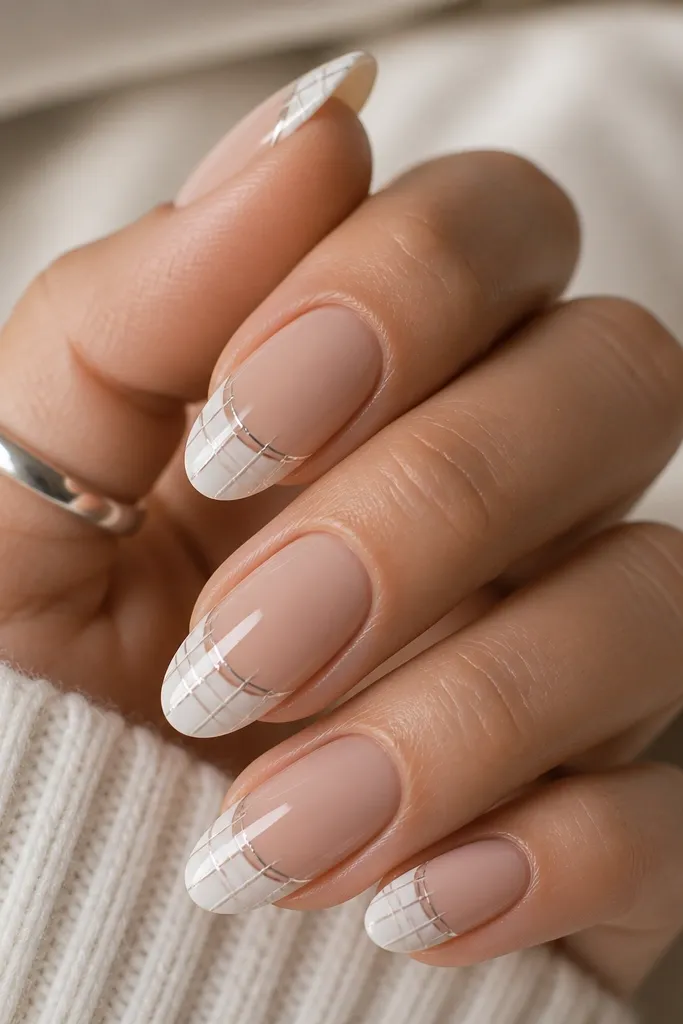 Short squoval nails with nude base and white French tips. Across the tips are thin silver micro lines forming a grid; glossy finish.
