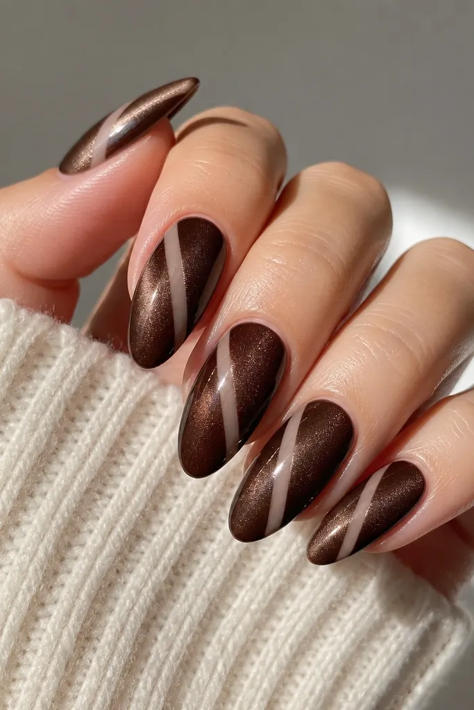 Chocolate cat eye nails with a diagonal clear negative-space strip from near one sidewall toward the opposite tip, leaving the stripe visible through the brown areas.