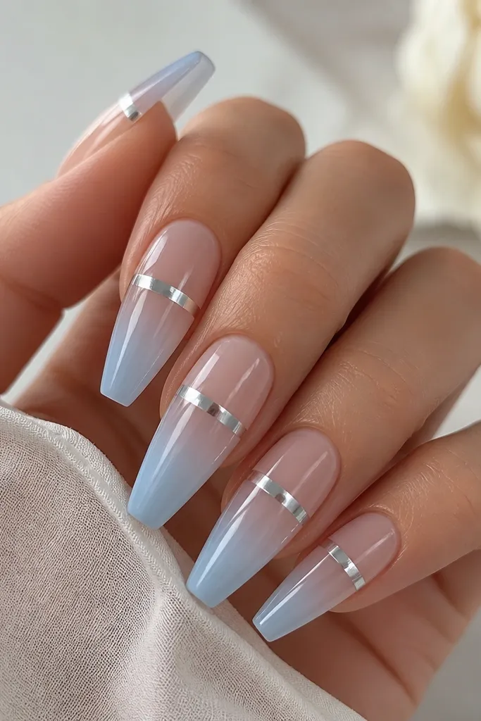 Coffin nails with a translucent jelly-like base fading into a soft sky-blue tip. Ice silver chrome is applied in a narrow strip across the upper third, like a frosty highlight.