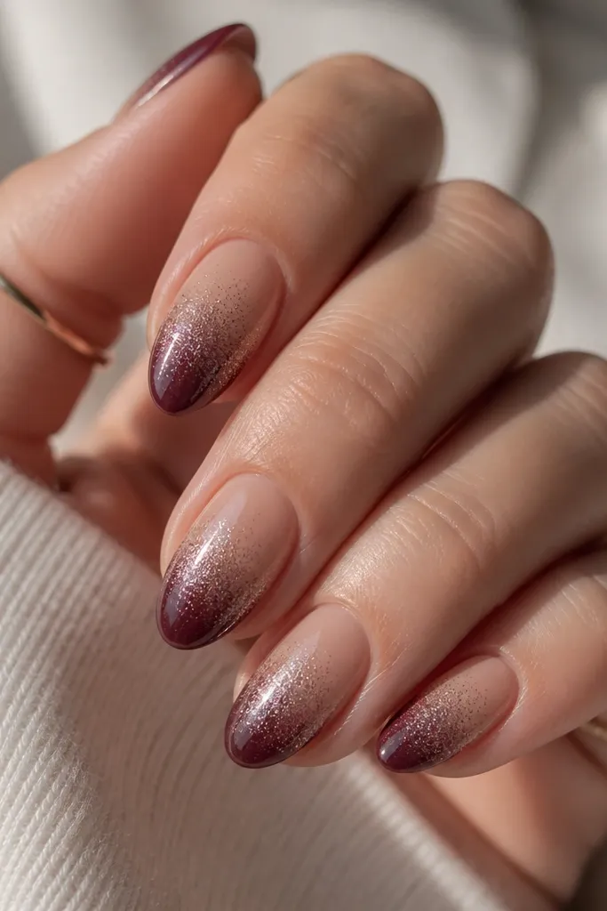 Short almond nails with beige nude at the cuticle fading into deep plum tips. Silver chrome appears as a light spark veil across the upper half, with more shine near the blend line.