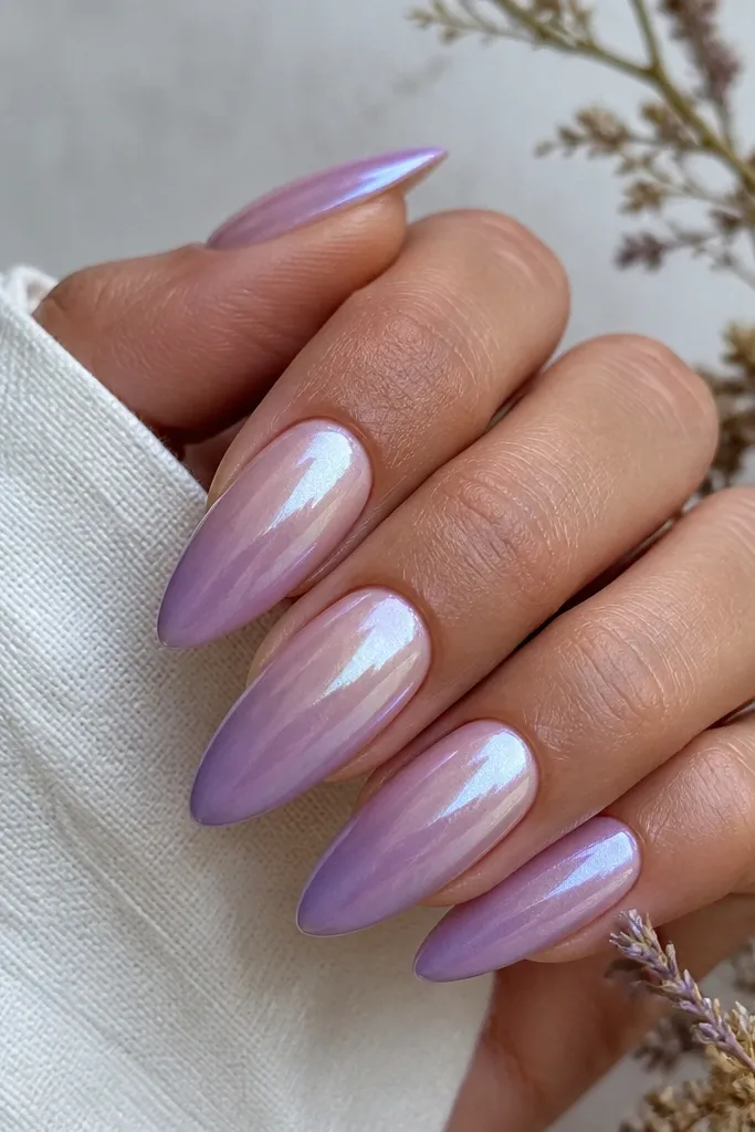 Long almond nails with pearl nude at the cuticle fading into lavender tips. Iridescent chrome glaze sits over the upper half, shifting between lilac and silver as it catches light.