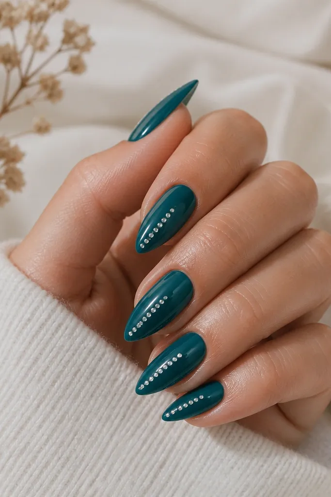 Short stiletto nails in jewel teal glossy. On each nail, there's a tiny row of clear micro rhinestones starting near the sidewall and running toward the tip. The rhinestones are small and evenly spaced.
