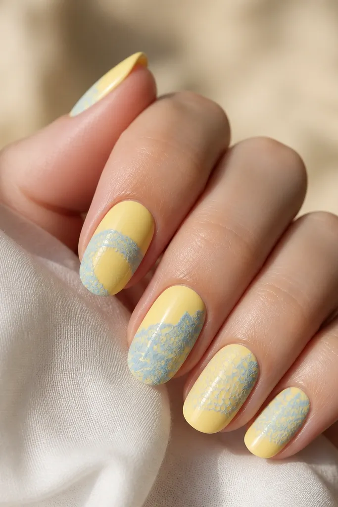 Yellow nails with a light blue lace pattern near the tips, like delicate net lines and small dot clusters. Glossy.